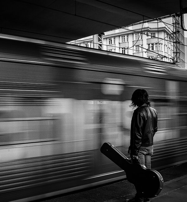 man with guitar waiting for train